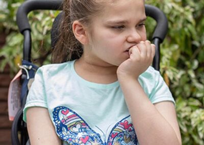 A girl with a butterfly shirt in front of greenery